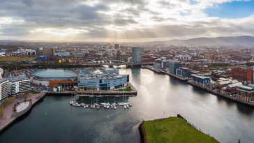 An aerial view of Belfast that showcases sun rays through gray clouds.