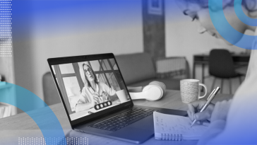 Two women on a Zoom call. The woman on the screen is explaining something while the woman in person is taking notes.