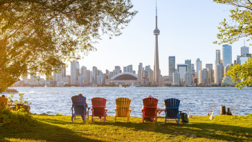 A view of the Toronto skyline from behind five colorful lawn chairs.