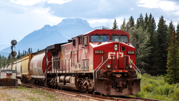 A Canadian Pacific locomotive at the station in Banff with forests and mountains in the distance