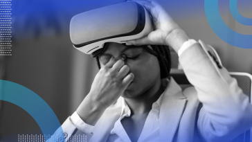 A woman lifting a VR headset off her face while pinching the bridge of her nose from a headache.