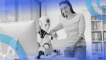 A woman shows a page of text to a robotic collaborator in front of a desktop terminal