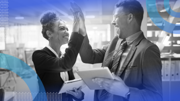 Two businesspeople high five while holding tablets