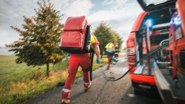 A paramedic rushes from an emergency vehicle.