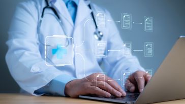 Physician typing on a computer displaying digital healthcare icons. 