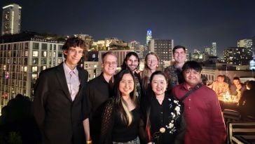 Isabel Zhang (front, left) stands with team members on a rooftop at night