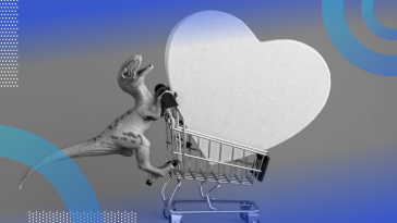 A toy dinosaur pushing a tiny shopping cart with a big heart in it.