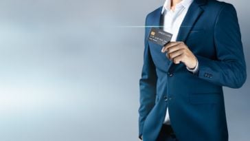 Man in suit holds credit card.