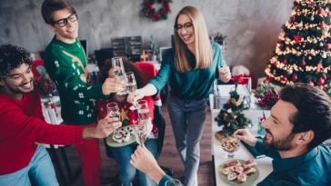 Employees wearing festive sweaters clinking glasses at a holiday party