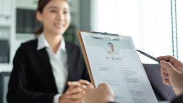 A hiring manager holds an employee's resume while interviewing them.