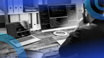 Software developer writing code and reviewing multiple monitors