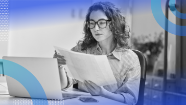 A woman software developer with glasses looks at documentation