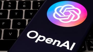 OpenAI logo on a smartphone resting on top of a laptop keyboard.