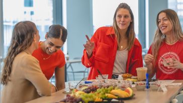 A photo of CarGuru employees talking around a kitchen table in an office setting. 