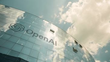 Image looking up at front facade of OpenAI office, with clouds hovering above. 
