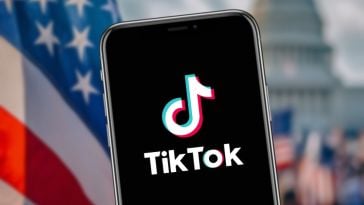 A smartphone with TikTok on it against the backdrop with the U.S. Capitol and American flags.