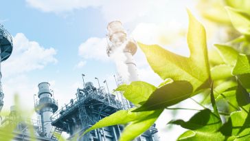 An industrial plant overlaid by bright green leaves.