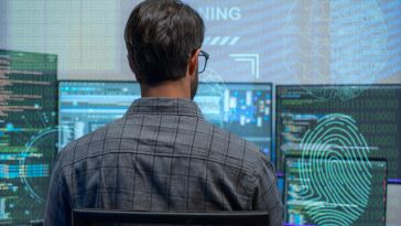 man working at multiple computer screens