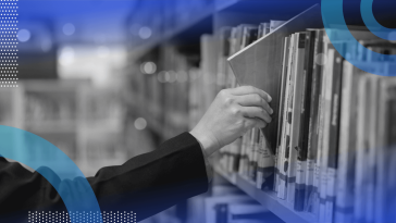 A hand takes a book off a library shelf