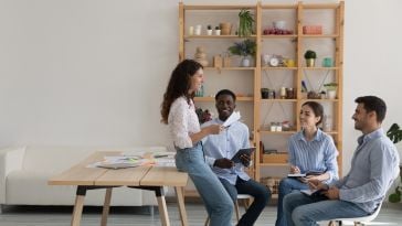 Four team members discuss a new sales strategy while working together in an office