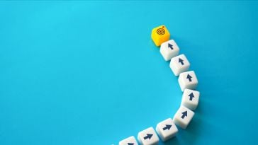 White arrow blocks pointing to a target yellow block on a blue background to show the idea of purpose at work. 