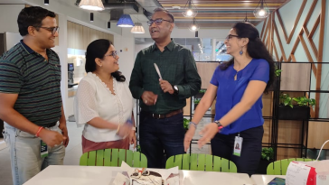 A group of ServiceNow employees talking in an office kitchen.