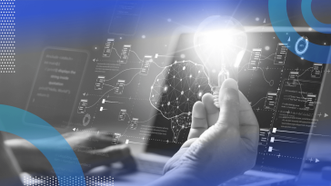 A user works at a laptop while holding a light bulb