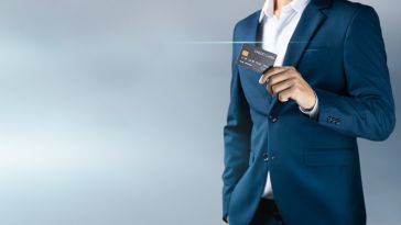 A man in a suit holds up a credit card.