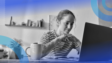 A remote worker looks at her laptop with a cup of coffee nearby