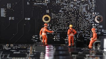 A photo of miniature figures building a motherboard to show the idea of dev teams building new tech.