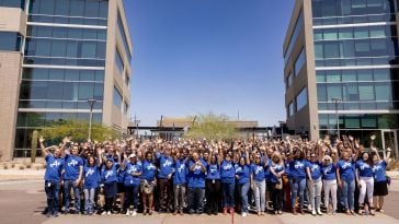 Several colleagues chatting together over coffees in the office while working on a project