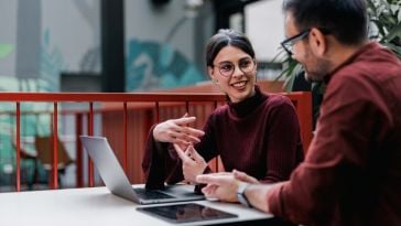 An intern chats with her colleague while working on an assignment in the office