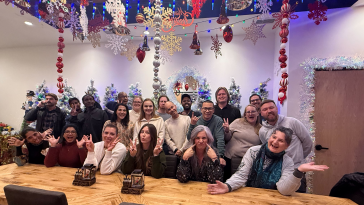 TrueML coworkers smiling at a long wooden table during a holiday party
