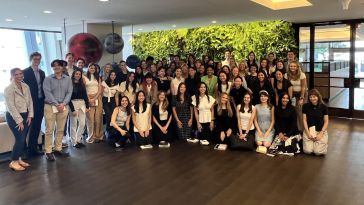 A photo of Tapestry interns together for a group photo in front of a green wall. 
