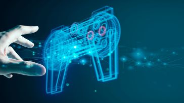 A digital hand reaches for a glowing, wireframe gaming controller on a dark blue background, symbolizing virtual interaction and technology.