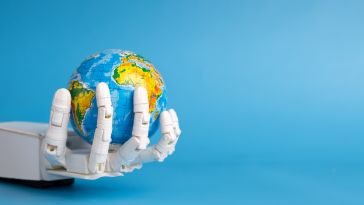 A robotic hand holds a small model of the globe, with a light-blue background.