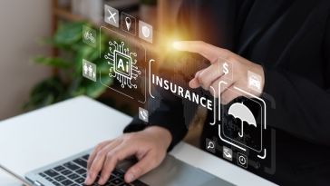 Person types on laptop with one hand and uses the other to click on an insurance hologram.