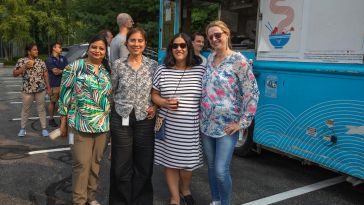 A group of Advisor360° employees pose together outside in a parking lot. 
