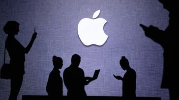 Silhouettes of people using technology in front of Apple logo