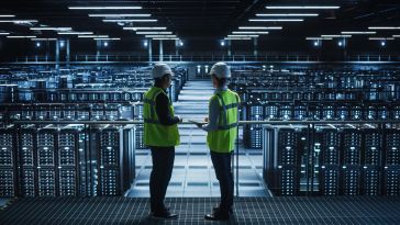 Two data center technicians talk to each other in a data center.