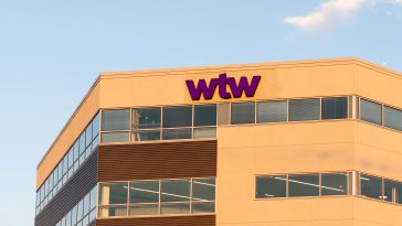 The upper corner of a modern office building with the "wtw" logo in purple on the facade, under a clear sky.