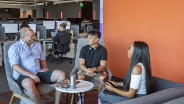 Three DraftKings team members meet in a collaboration space in the company’s office