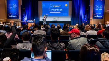 A group of Optimum employees in the audience of a hackathon.