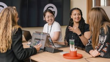 Four Superhuman team members chat while working on a project together in the office