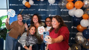 Several Zoro team members pose for a photo while holding signs during a company event