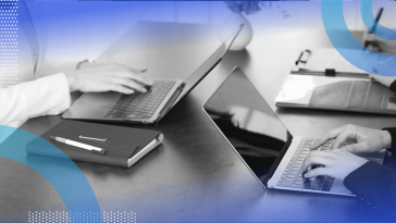 A closeup on developers working on laptops with a notebook on the table
