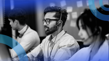 A software engineer in front of a kanban board speaks on a headset