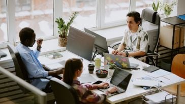 A group of young professionals type prompts into AI chatbots.