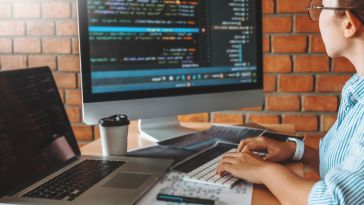 Software engineer coding on desktop and laptop computer
