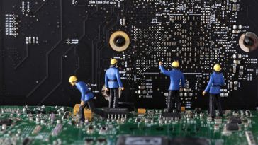 An image of miniature figures working on a computer’s motherboard to show the idea of working on a software engineering team.